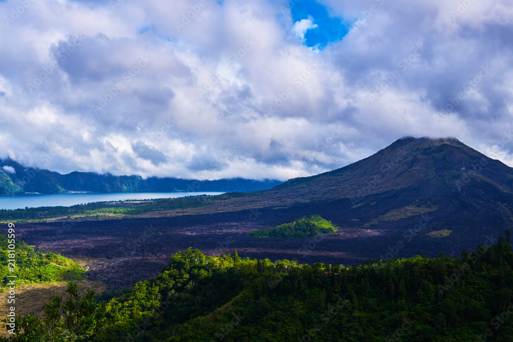 Summer background. Rural sunrise landscape. Countryside and green tropical forest. Natural background. Landscape of Batur volcano on Bali island, Indonesia. Azure lake in the mountains.