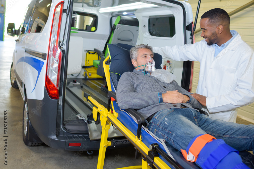 Patient wearing oxygen mask being loaded into ambulance Patient wearing oxygen mask being loaded into ambulance