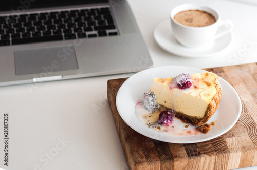 Сoffee cappuccino and dessert cheesecake at the work table. concept of lunch in office at work. breakfast for laptop. top view.