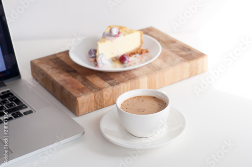Сoffee cappuccino and dessert cheesecake at the work table. concept of lunch in office at work. breakfast for laptop. top view.