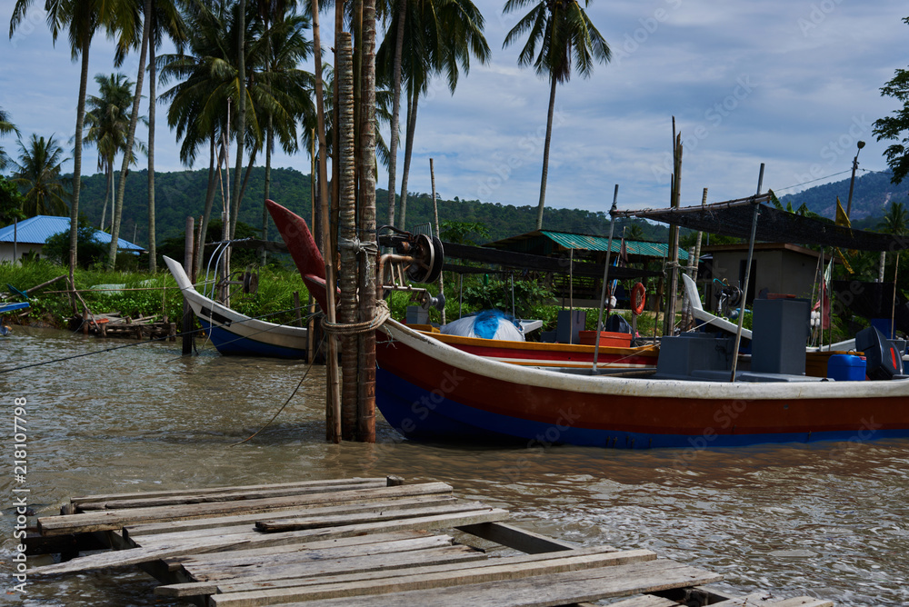Boats parked in fishing village. Fisherman village. Many fishing boats moored at old wooden pier. Traditional thai fisherman long tail boat in a fishermen village, Thailand, Asia.