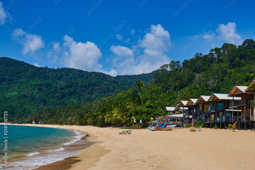 Beach bungalows on a tropical island, travel background. Tropical island landscape. Tioman island beach in Malaysia. Summer vacation holiday concept. Beach natural background, summer background.