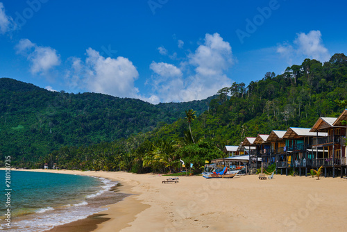 Beach bungalows on a tropical island, travel background. Tropical island landscape. Tioman island beach in Malaysia. Summer vacation holiday concept. Beach natural background, summer background. © eskstock