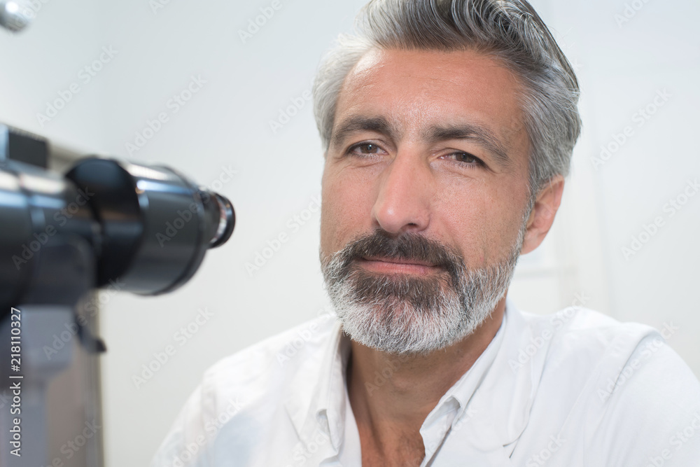 Closeup of laboratory worker next to microscope eyepiece Closeup of laboratory worker next to microscope eyepiece