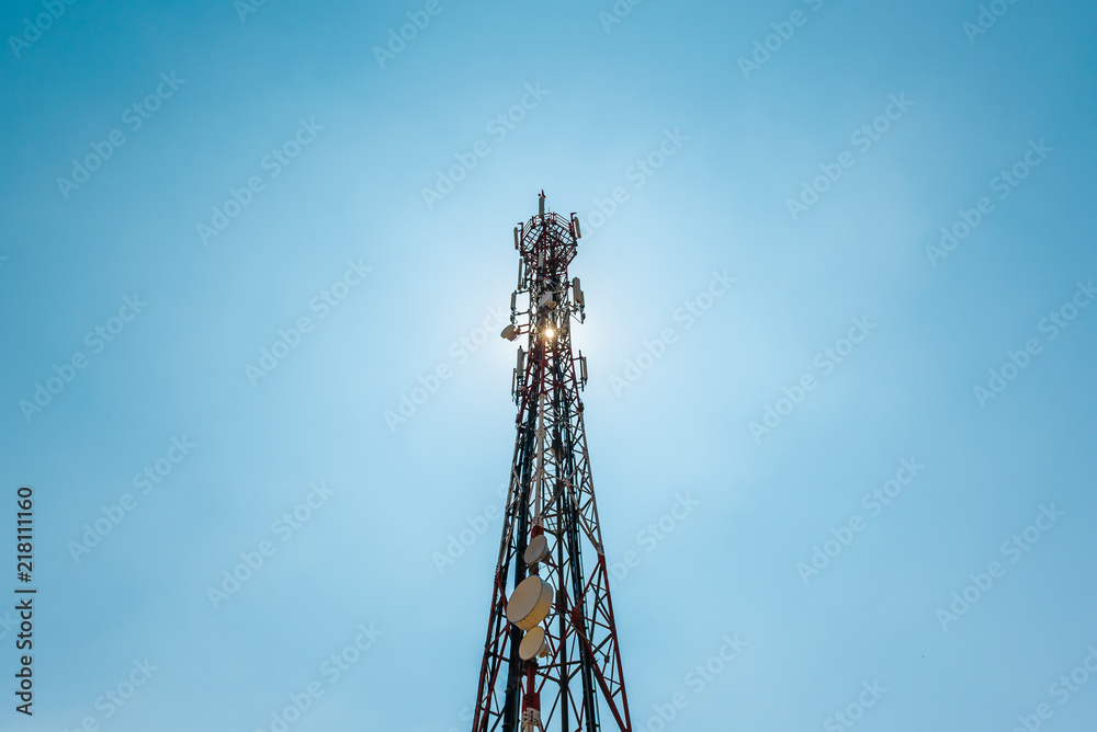 Telecommunication TV antennas with cell phone antennas and satellite dish with blue sky in background Telecommunication TV antennas with cell phone antennas and satellite dish with blue sky in background