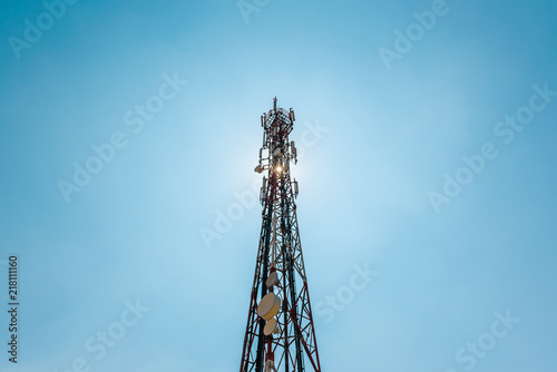 Telecommunication TV antennas with cell phone antennas and satellite dish with blue sky in background