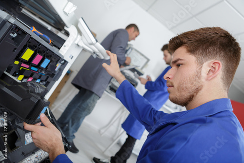 Young man maintaining photocopier