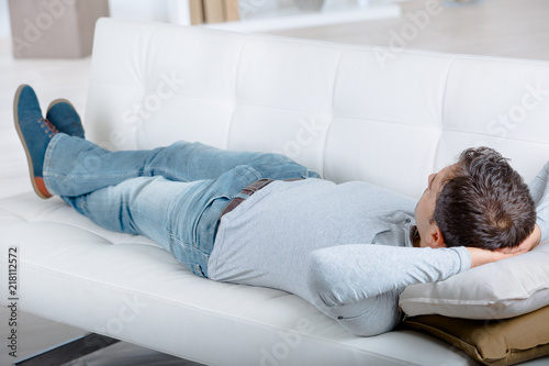 young tired man lying on sofa after cleaning