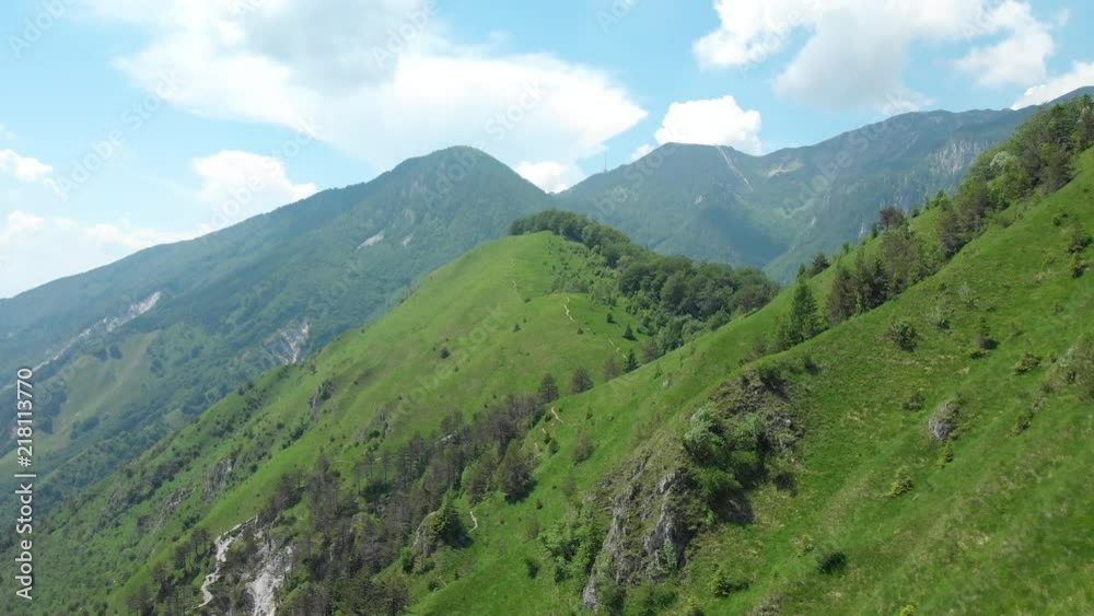 AERIAL: Flying along a steep grassy mountain in the breathtaking sunny Alps. Spectacular shot of the green mountain range under the clear blue sky in Slovenia. Picturesque alpine nature in summer. AERIAL: Flying along a steep grassy mountain in the breathtaking sunny Alps. Spectacular shot of the green mountain range under the clear blue sky in Slovenia. Picturesque alpine nature in summer.