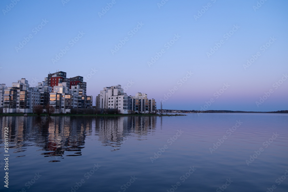 A complex of appartment buildings in the center of Swedish town Vasteras,  located near the large lake,  during sunset with blue and  purple sky reflecting in the water 