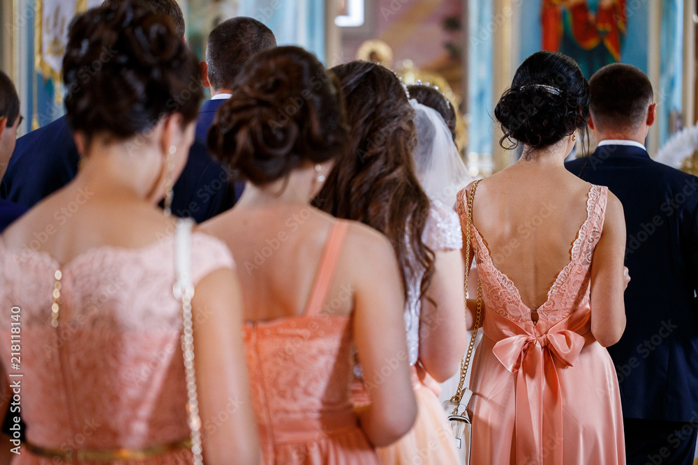 bridesmaids and witnesses stand with their backs in the church