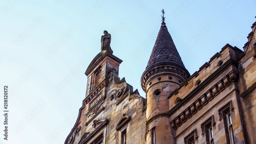 Statue and pretty turret atop a Victorian red sandstone building in Dalintober Street, Glasgow.
