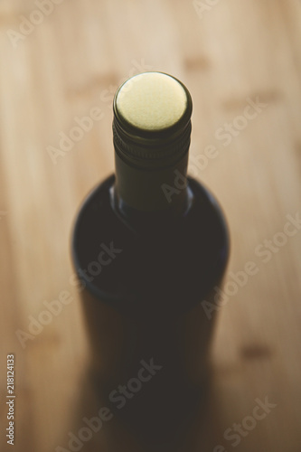 A black bottle of wine on a wooden table top. This image can be used to represent wine drinking. 