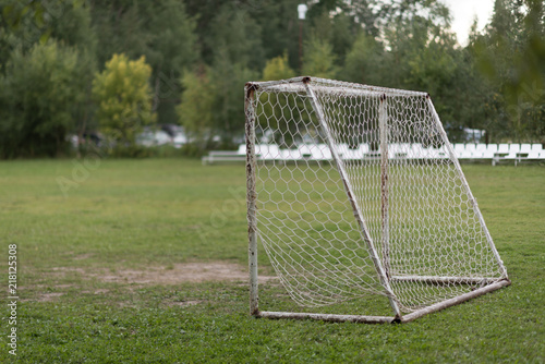 Old vacant football soccer goal gate in rural grass field. Old sports field with rusty goal and net on meadow with muddy front line. © Mak