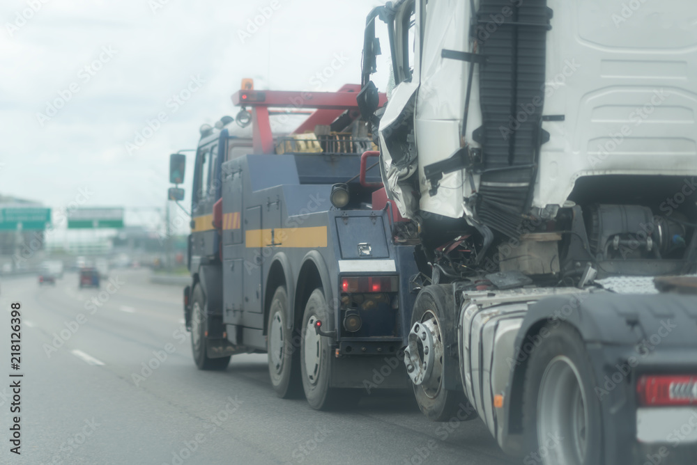 Blue Tow truck delivers the damaged white lorry, Sun light flare, Selective focus. Asphalt highway