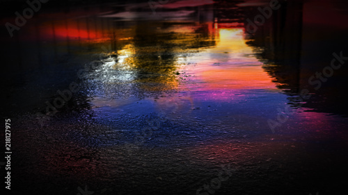 Light and shadows of the night city. Wet asphalt with neon. Soft image of the focus of the street after the rain with reflections on the wet asphalt. Blurred background.