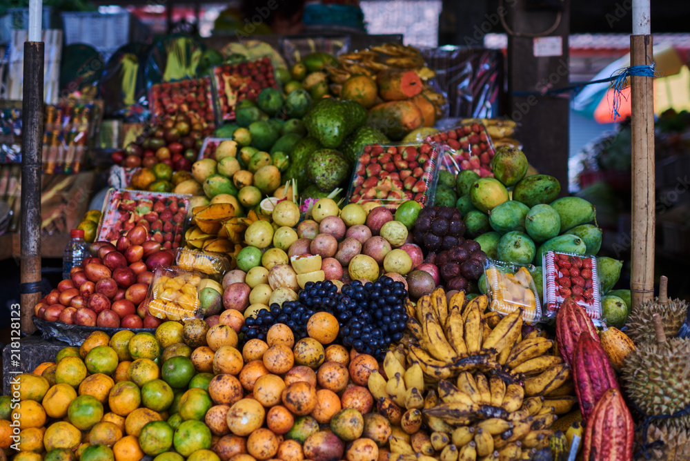 Different kind and mix of many fresh tropical fruits and berries lying on market stall. Beautiful display of exotic fruits at a local market in Indonesia. Assortment at a street market.