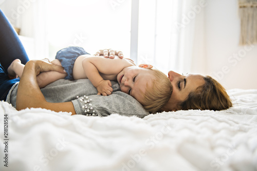 Mother and baby girl on a white bed