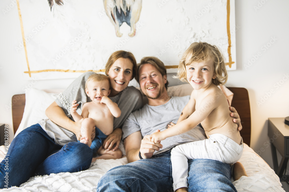 Family of four with baby having fun on bed