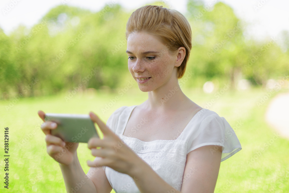 Cute woman is reading pleasant text message on mobile phone while sitting in the park in warm spring day,gorgeous female is listening to music and searching information on cell telephone Cute woman is reading pleasant text message on mobile phone while sitting in the park in warm spring day,gorgeous female is listening to music and searching information on cell telephone