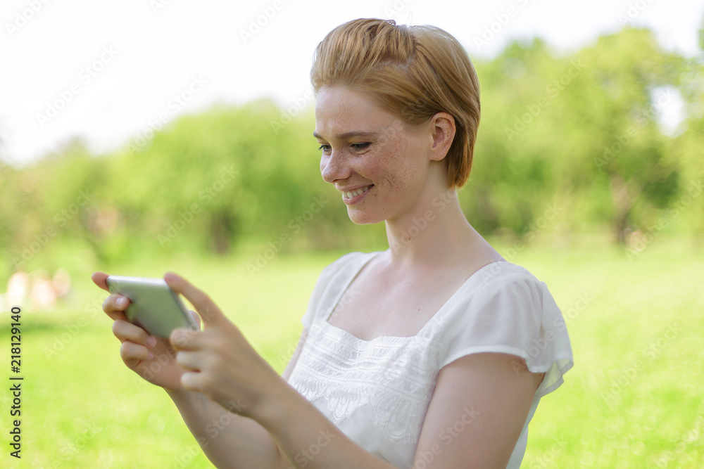 Cute woman is reading pleasant text message on mobile phone while sitting in the park in warm spring day,gorgeous female is listening to music and searching information on cell telephone Cute woman is reading pleasant text message on mobile phone while sitting in the park in warm spring day,gorgeous female is listening to music and searching information on cell telephone