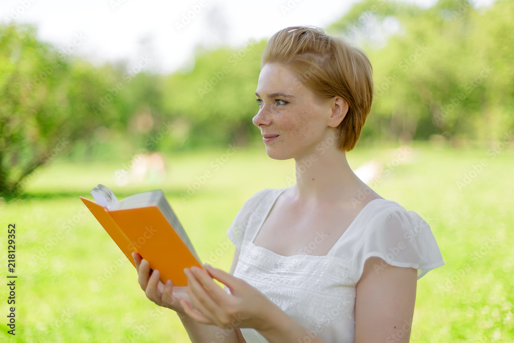 serious young, beautiful girl holding an open book, read background summer green park serious young, beautiful girl holding an open book, read background summer green park