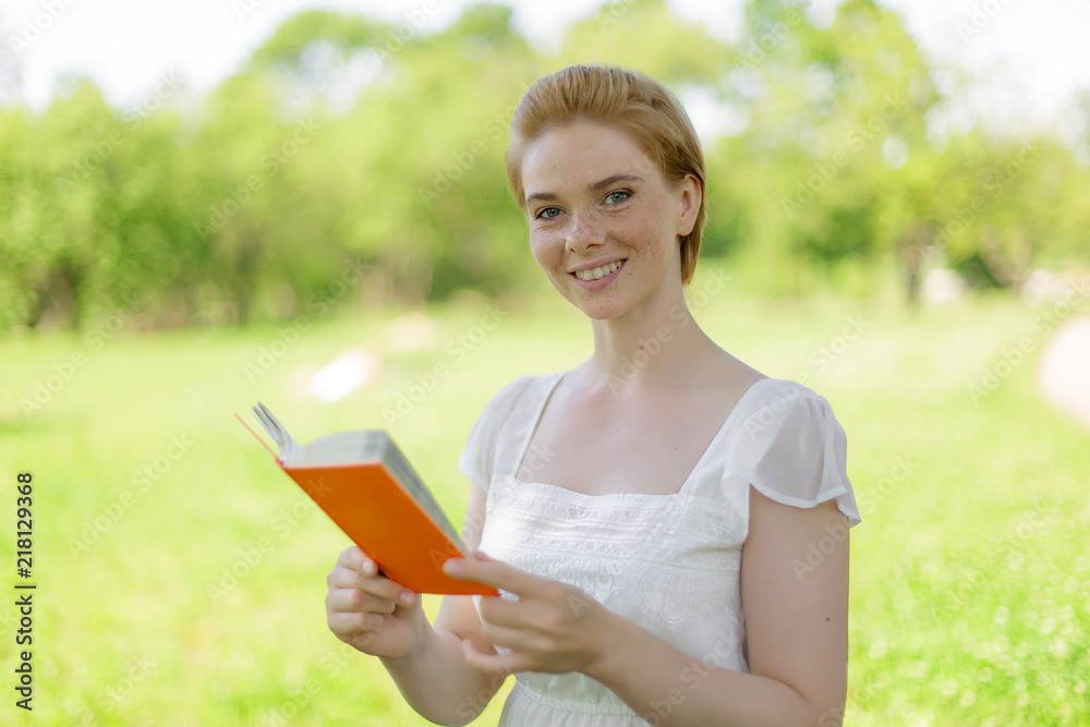 serious young, beautiful girl holding an open book, read background summer green park serious young, beautiful girl holding an open book, read background summer green park