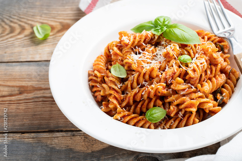 Fusilli pasta with tomato sauce, garlic, Basil and Parmesan cheese on an old wooden table. with copy space