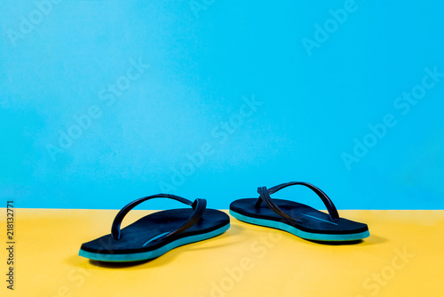 Black and green Flip-flops, summer set. Summer is coming concept. Minimal style, minimalist photography. Yellow, pink and blue pastel colors background.