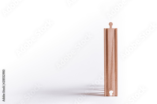 Wooden block isolated on a white background. The wooden block casts shadows, and other blocks are stacked behind it.