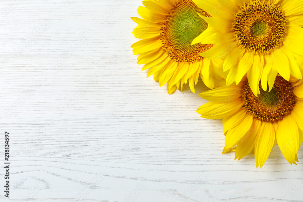 Fototapeta premium Yellow sunflowers on wooden background, top view