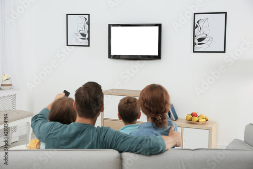Family watching TV in room at home