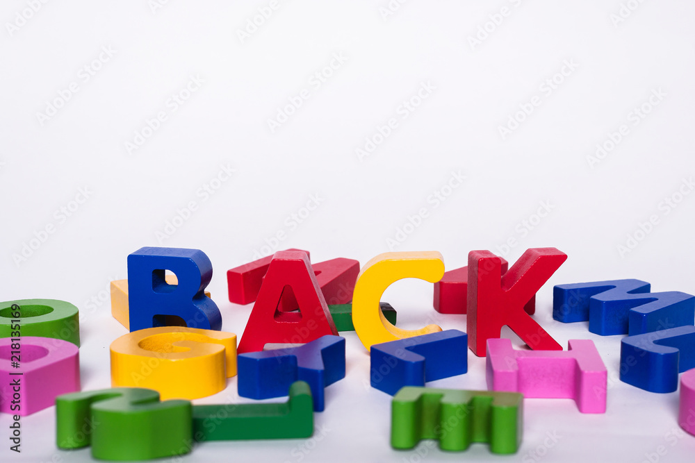 Naklejka premium Scattered various colorful and wooden letters on a white background with an inscription BACK.