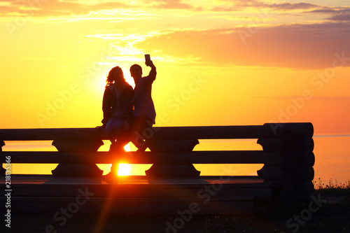 Silhouette young couple at sunset by the sea. Selfie