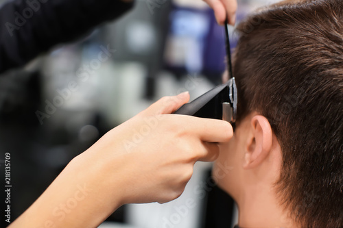 Professional stylist cutting client's hair in salon, closeup