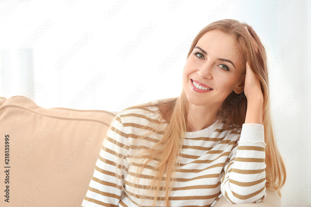 Beautiful smiling woman relaxing on sofa in room Beautiful smiling woman relaxing on sofa in room