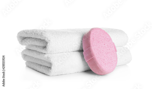 Stack of clean soft towels and sponge on white background