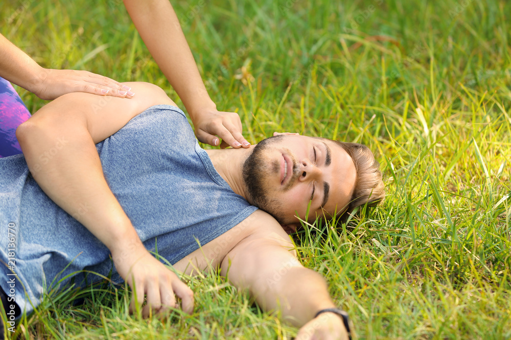 Woman checking pulse of unconscious man outdoors Woman checking pulse of unconscious man outdoors