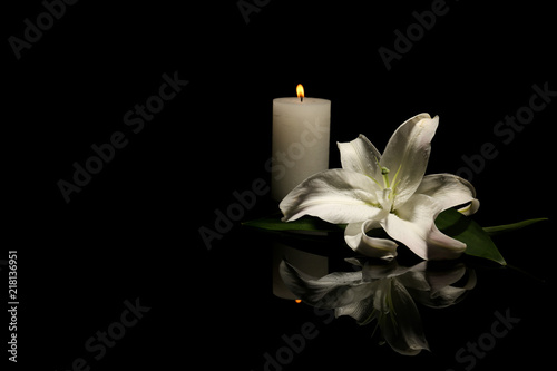 Canvas Print Beautiful lily and burning candle on dark background with space for text