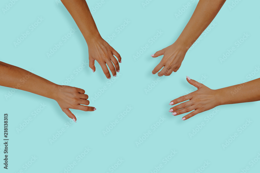 Top view of female hands with nails on a blue, pastel background. Female hands reach for something in the middle of the table. The concept of desire, the desire to receive something.