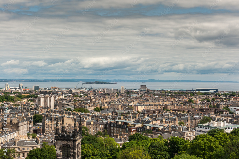 Edinburgh, Scotland, UK - June 13, 2012: Looking from Calton Hill over densely built Leith suburb towards the Nord Sea inlet under a heavy cloudscape. Island and other side of water.