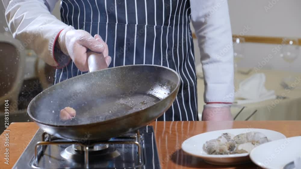 Eating out. Food preparation. Close up of chef holding a pan with boiling oil and a garlic. slow motion. oil splashes Eating out. Food preparation. Close up of chef holding a pan with boiling oil and a garlic. slow motion. oil splashes
