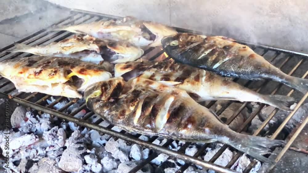 Mediterranean fish on a grill. Summer barbeque hand marinade the fish. Very rustic style. Real fire grill. Mediterranean fish on a grill. Summer barbeque hand marinade the fish. Very rustic style. Real fire grill.