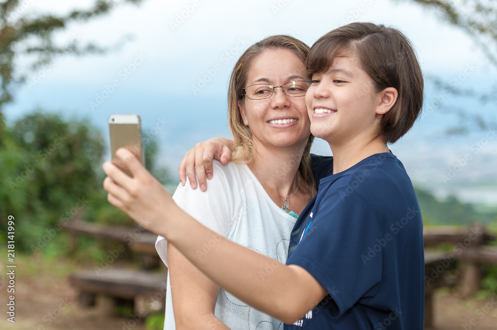 Young mother and teenage daughter taking a selfie in a very beautiful place outdoors (mixed race - Brazilian / Japanese). Young mother and teenage daughter taking a selfie in a very beautiful place outdoors (mixed race - Brazilian / Japanese).