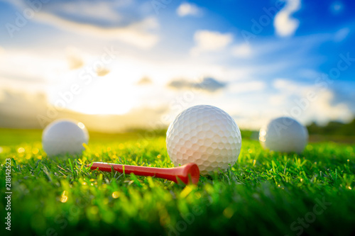 Photographie close up the golf ball and red tee pegs on the green background with sunset