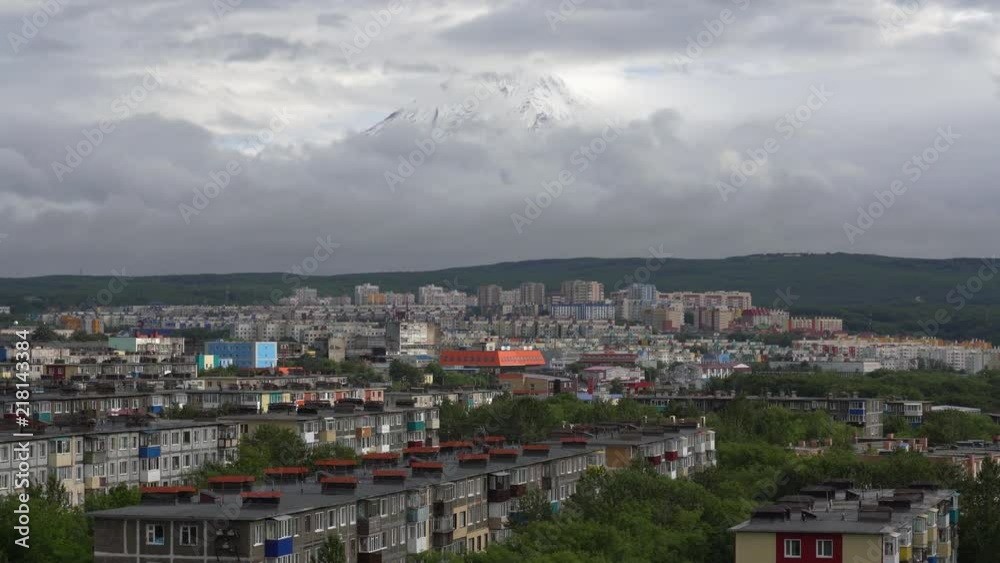 Summer cityscape of Kamchatka Peninsula: view of urban development of Petropavlovsk-Kamchatsky City on background of volcano, clouds floating across sky, around mountains. Russian Far East. Time lapse Summer cityscape of Kamchatka Peninsula: view of urban development of Petropavlovsk-Kamchatsky City on background of volcano, clouds floating across sky, around mountains. Russian Far East. Time lapse