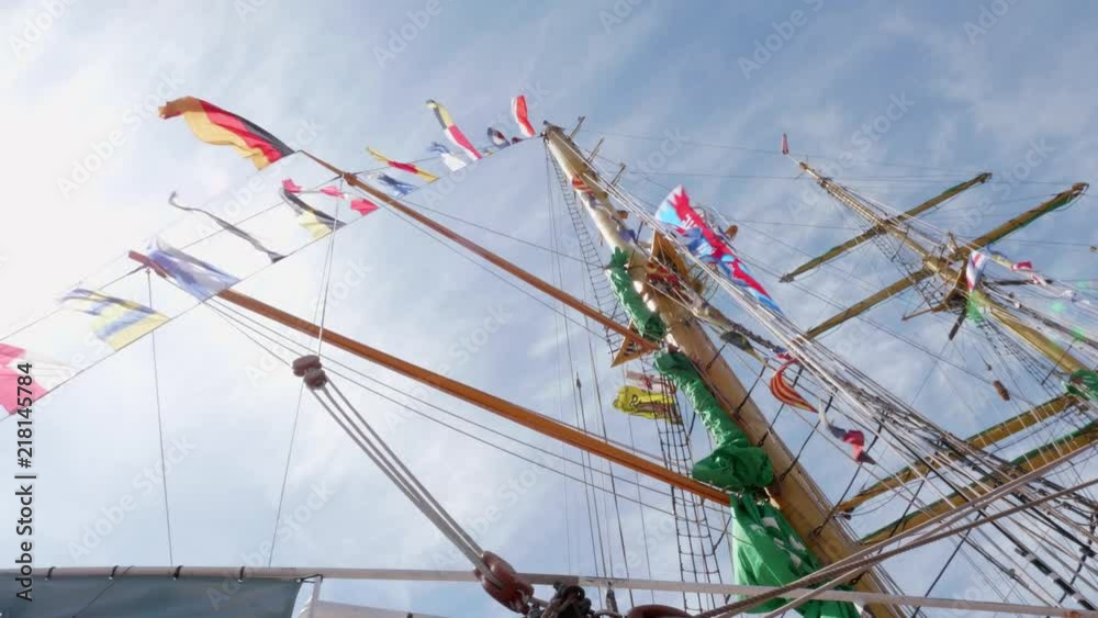 A shot of the masts of a tall ship with a lot of flags attached to it ...