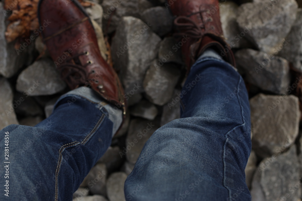Legs standing on rocks, brown boots and denim Legs standing on rocks, brown boots and denim
