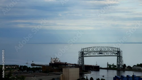 Iron ore ship going under the historic aerial lift bridge in Duluth, Minnesota under cloudy skies, leaving the Great Lake Superior and entering Duluth Harbor. photo