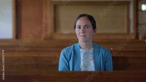 A portrait of a young Mennonite woman sitting in an empty church in slow motion. photo